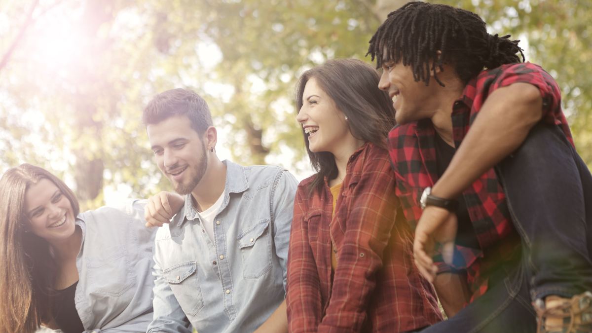 Vier Menschen sitzen lachend im Grünen
